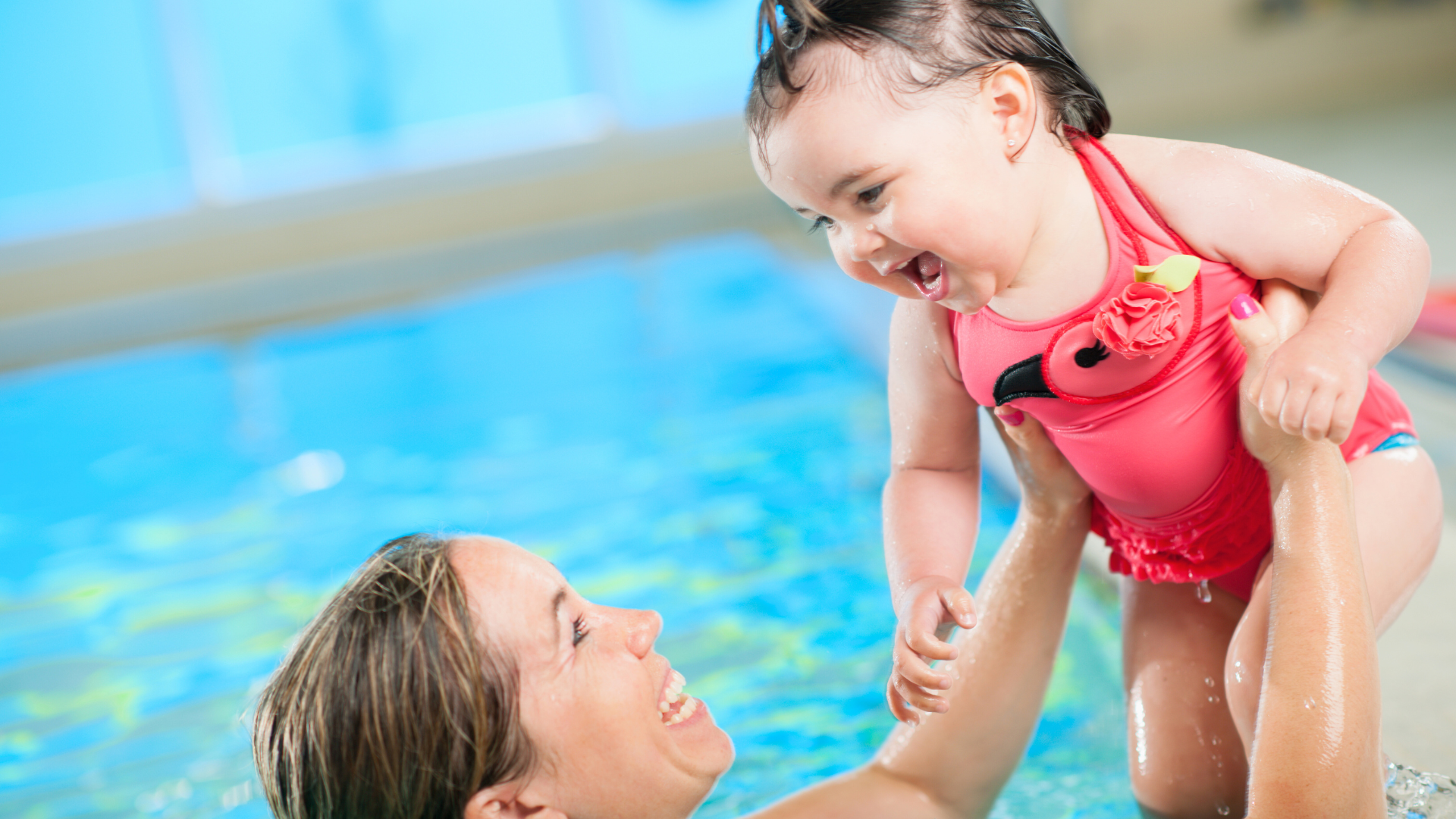 Mother holding baby up in a pool.png